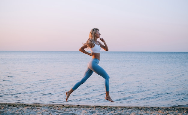 Mujer joven, jogging, por el océano