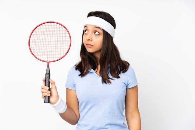 Mujer joven jugador de bádminton aislada haciendo gesto de dudas mirando de lado