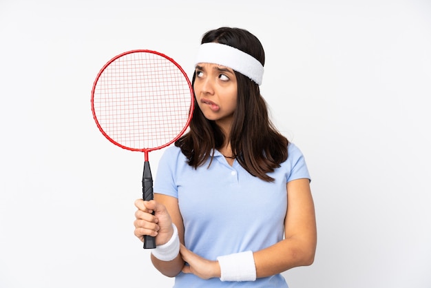 Mujer joven jugador de bádminton sobre pared blanca aislada con expresión de la cara confusa