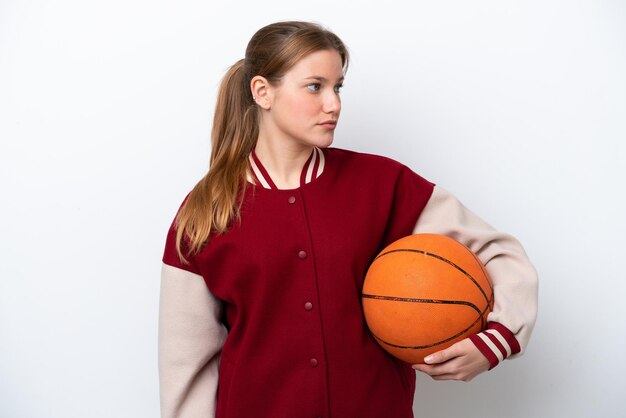 Mujer joven jugador de baloncesto aislado sobre fondo blanco mirando hacia el lado