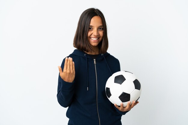 Mujer joven jugador de fútbol aislada en la pared blanca que invita a venir con la mano. Feliz de que hayas venido