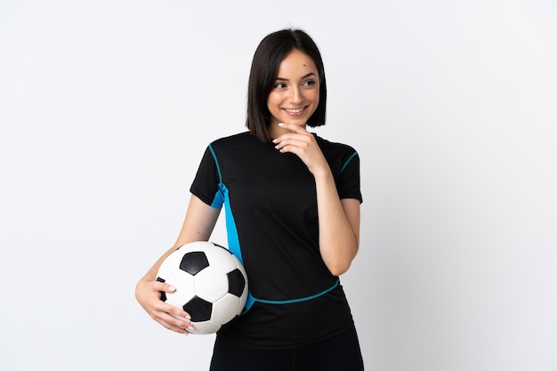 Mujer joven jugador de fútbol aislado en blanco mirando hacia arriba mientras sonríe