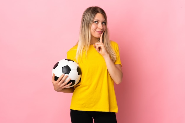 Mujer joven jugador de fútbol aislado en la pared rosa pensando en una idea