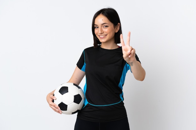 Mujer joven jugador de fútbol aislado sobre fondo blanco sonriendo y mostrando el signo de la victoria