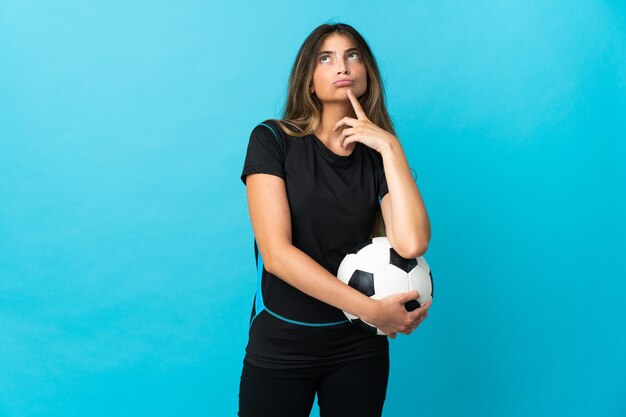 Mujer joven jugador de fútbol en azul con dudas mientras mira hacia arriba