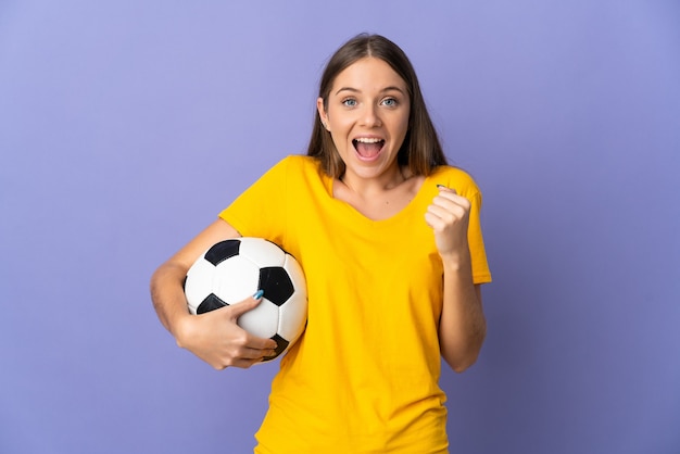 Mujer joven jugador de fútbol lituano aislada en la pared púrpura celebrando una victoria en la posición ganadora