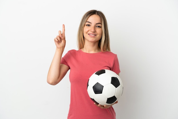 Mujer joven jugador de fútbol sobre pared blanca aislada apuntando hacia una gran idea