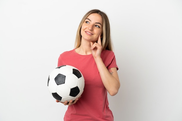 Mujer joven jugador de fútbol sobre pared blanca aislada pensando en una idea mientras mira hacia arriba