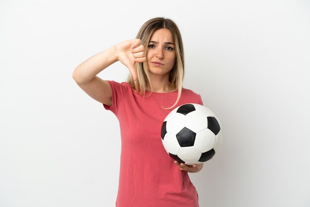 Mujer joven jugador de fútbol sobre pared blanca aislada que muestra el pulgar hacia abajo con expresión negativa