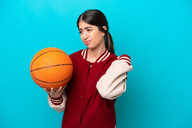 Mujer joven jugadora de baloncesto caucásica aislada de fondo azul que sufre de dolor en el hombro por haber hecho un esfuerzo