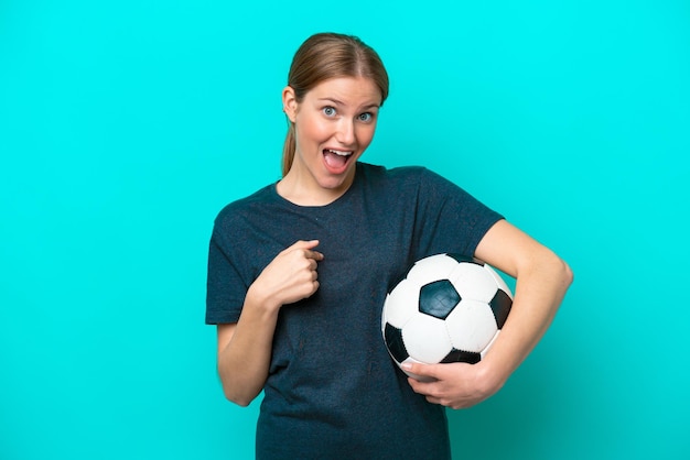 Mujer joven jugadora de fútbol aislada de fondo azul con expresión facial sorpresa