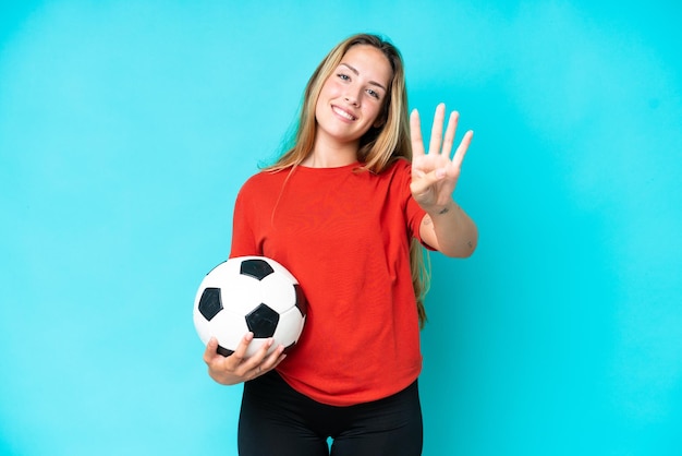 Mujer joven jugadora de fútbol aislada de fondo azul feliz y contando cuatro con los dedos