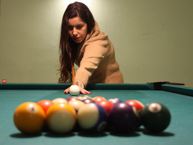 Foto mujer joven jugando al billar.