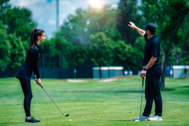 Mujer joven jugando al golf jugando al golf con instructor de golf