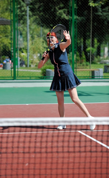 Mujer joven jugando al tenis al aire libre