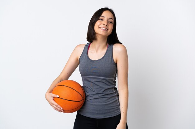 Mujer joven jugando baloncesto aislado en blanco riendo