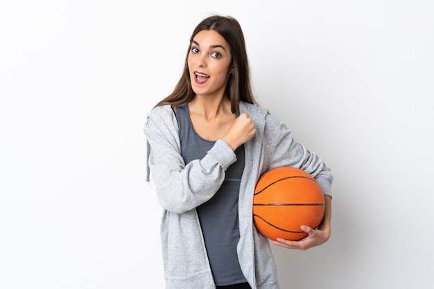 Mujer joven jugando baloncesto aislado en la pared blanca celebrando una victoria