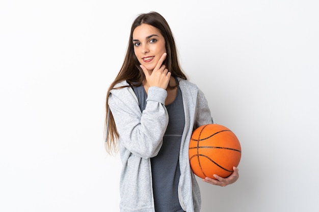 Mujer joven jugando baloncesto aislado sobre fondo blanco feliz y sonriente