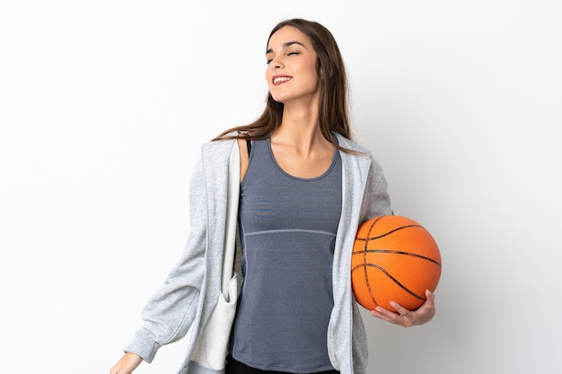 Mujer joven jugando baloncesto aislado sobre fondo blanco riendo