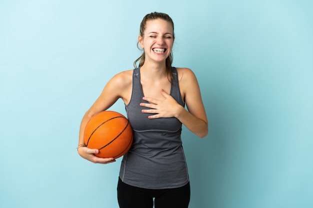 Mujer joven jugando baloncesto en azul sonriendo mucho