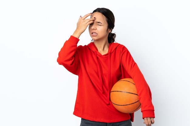 Mujer joven jugando baloncesto sobre blanco aislado con dolor de cabeza