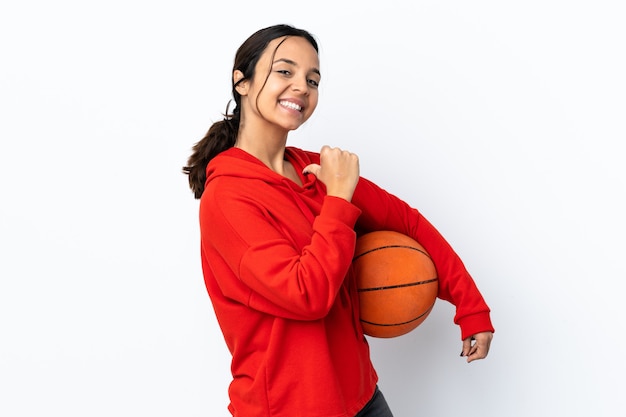 Mujer joven jugando baloncesto sobre pared blanca aislada orgulloso y satisfecho de sí mismo