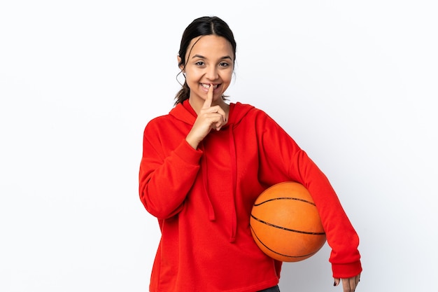 Mujer joven jugando baloncesto sobre pared blanca aislada que muestra un signo de silencio gesto poniendo el dedo en la boca