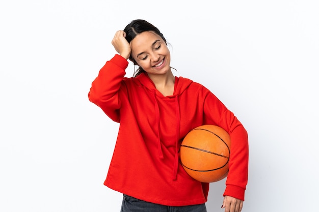 Mujer joven jugando baloncesto sobre pared blanca aislada riendo