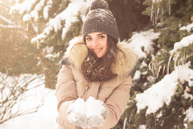 Mujer joven jugando con nieve y divirtiéndose
