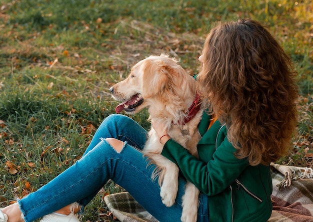 Mujer joven jugando con su perro golden retriever cerca del río en el parque