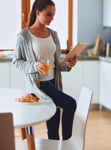 mujer joven, con, jugo de naranja, y, tableta, en, cocina