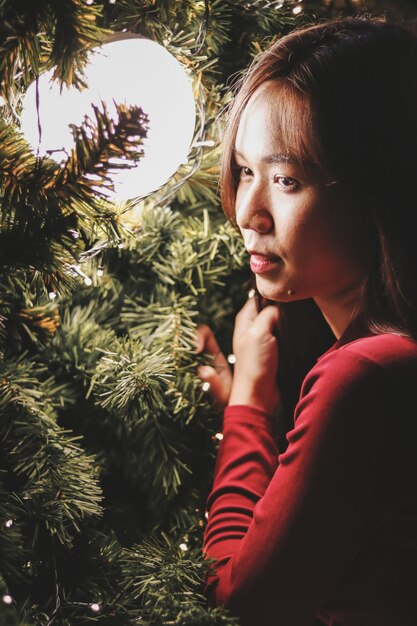 Mujer joven junto al árbol de Navidad iluminado