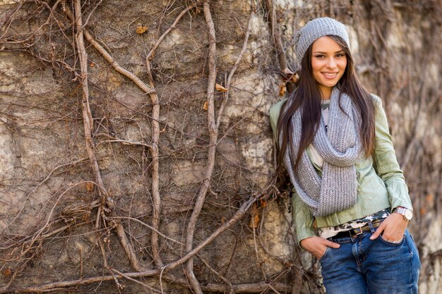 Mujer joven junto a la pared en otoño