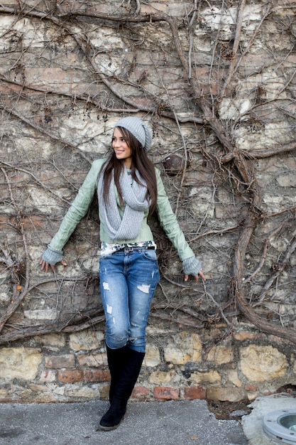 Mujer joven junto a la pared en otoño