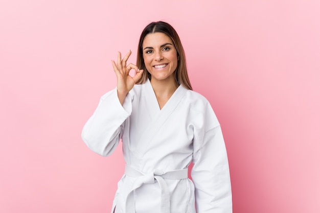 Mujer joven del karate alegre y confiada que muestra gesto aceptable.