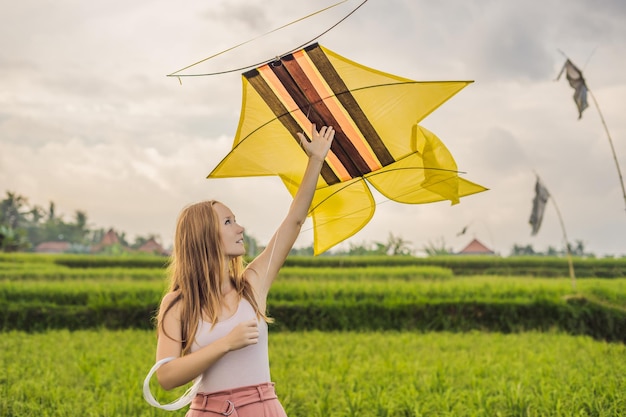 Mujer joven lanza una cometa en un campo de arroz en la isla de Ubud, Bali, Indonesia