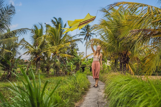 Mujer joven lanza una cometa en un campo de arroz en Ubud, isla de Bali, Indonesia