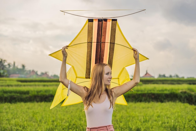 Mujer joven lanza una cometa en un campo de arroz en Ubud, isla de Bali, Indonesia