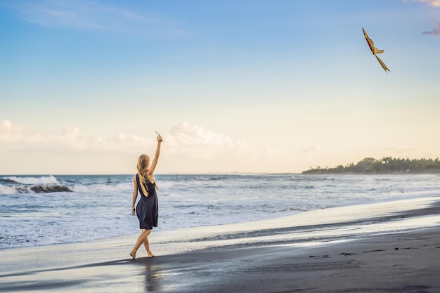 Una mujer joven lanza una cometa en la playa Sueño aspiraciones planes futuros