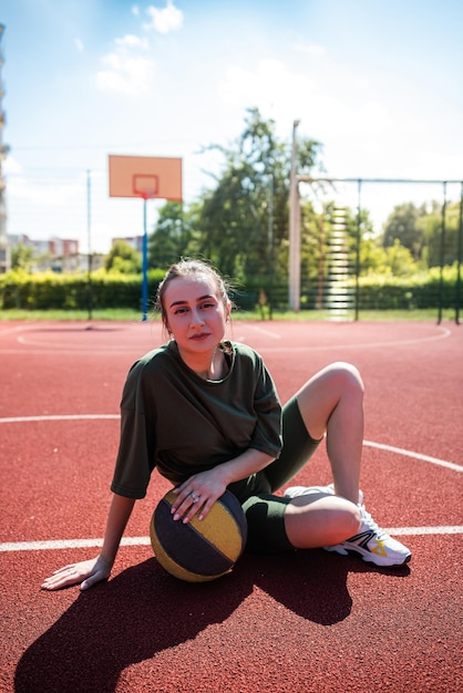 Mujer joven lanza una pelota de baloncesto al aire libre en un día soleado