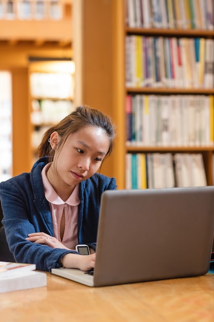 Mujer joven con laptop en la biblioteca