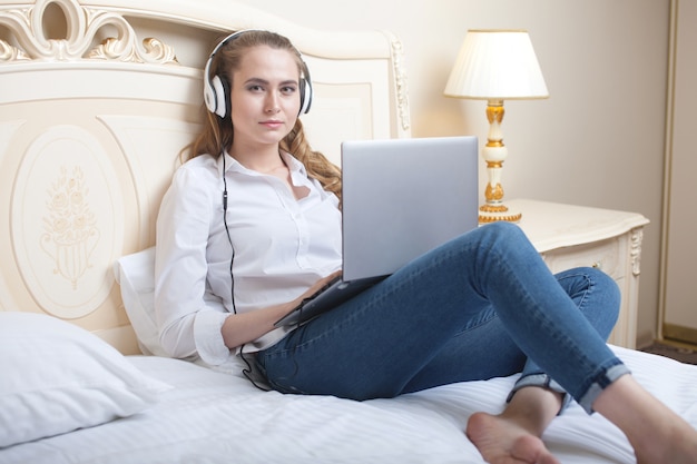 Mujer joven con laptop en la cama