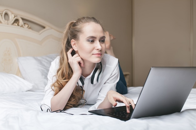 Mujer joven con laptop en la cama