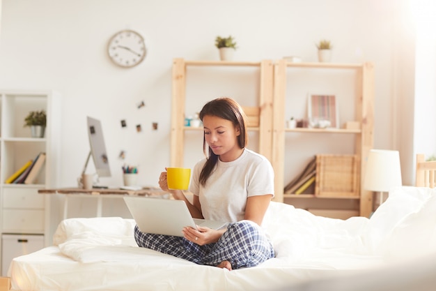 Mujer joven con laptop en la cama