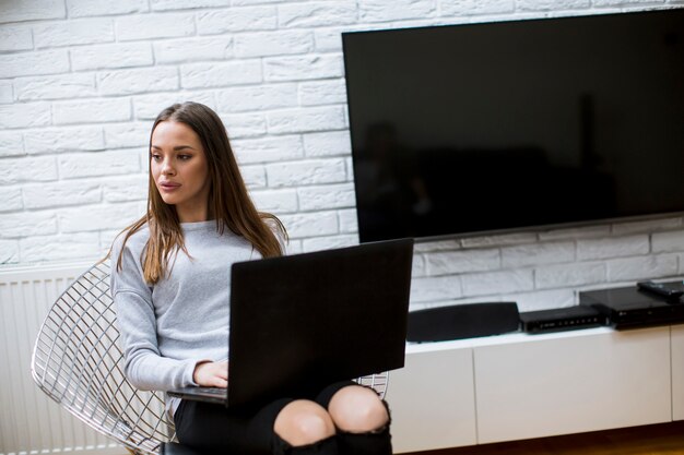 mujer joven con laptop en casa