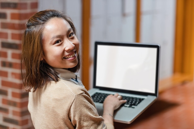 Mujer joven con laptop en corredor