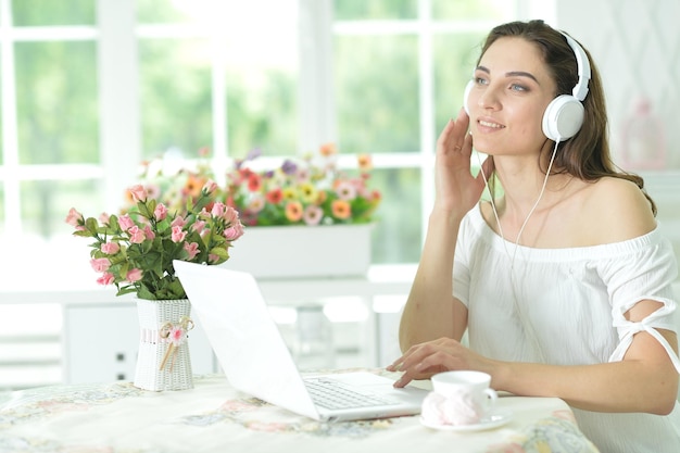 Mujer joven con laptop escuchando música
