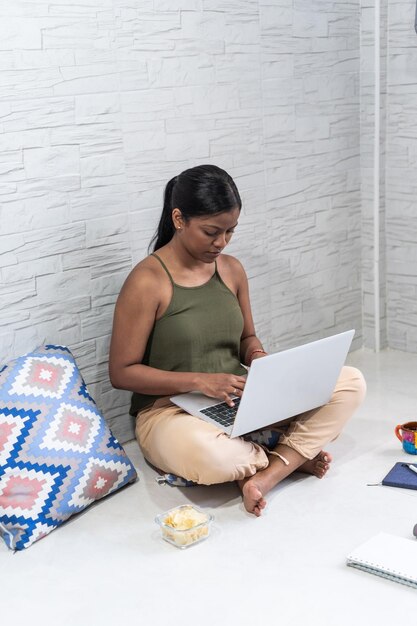 Mujer joven con laptop trabajando en casa