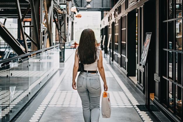 Mujer joven latina moderna caminando en un gran centro comercial moderno joven consumidora morena bonita