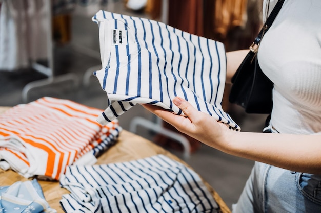 Mujer joven latina moderna que elige porcentaje de ropa de algodón orgánico en una tienda ecológica moderna